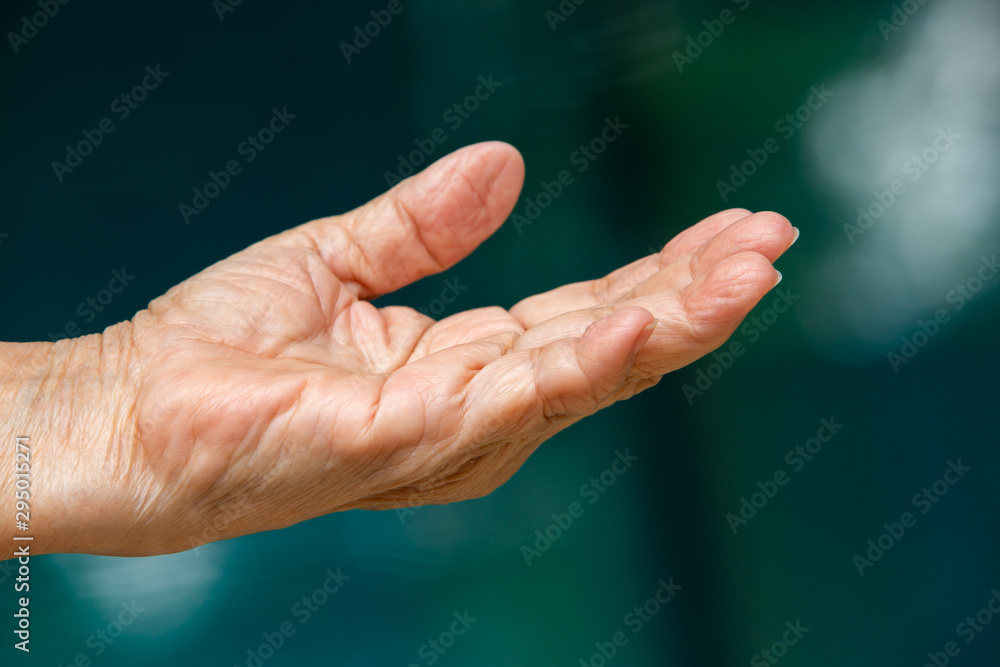 Senior woman's left hand showing something over her hand in bokeh blue swimming pool background, Asian body skin part, Symbol, Gesturing, Body Language concept Senior woman's left hand showing something over her hand in bokeh blue swimming pool background, Asian body skin part, Symbol, Gesturing, Body Language concept