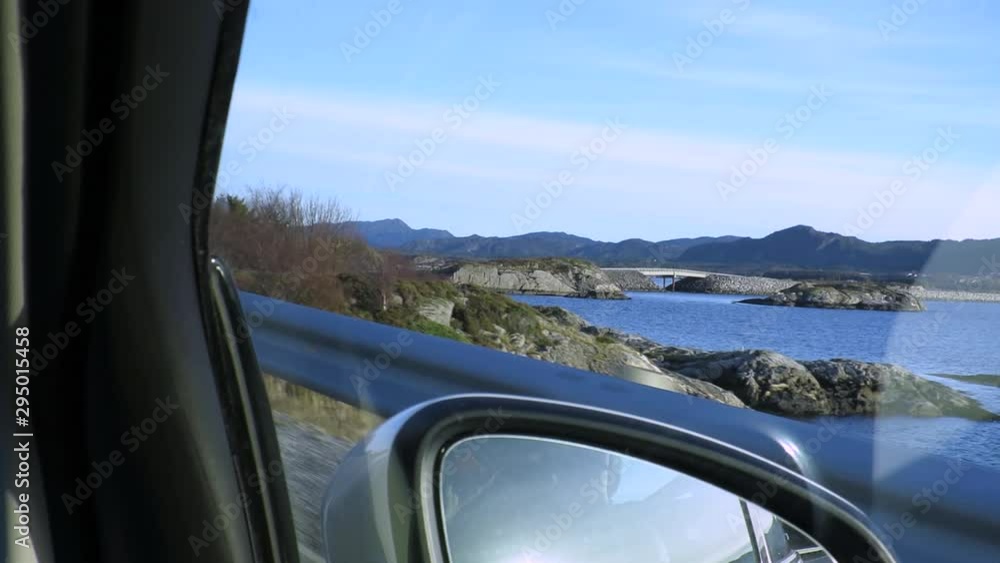 Car moving forward passing through beautiful scenic landscape with a wide lake and mountains as background Car moving forward passing through beautiful scenic landscape with a wide lake and mountains as background