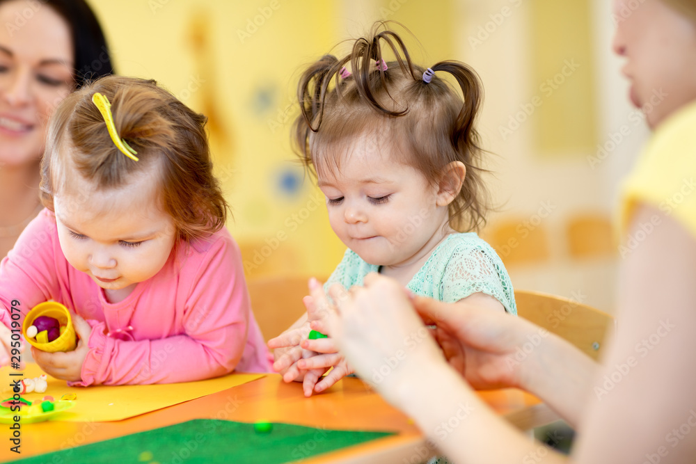 Fototapeta premium Children toddlers playing with plasticine at kindergarten or playschool