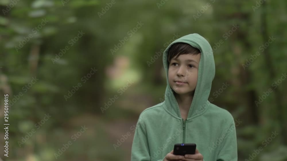 boy walking in the forest and uses a phone outdoors boy walking in the forest and uses a phone outdoors
