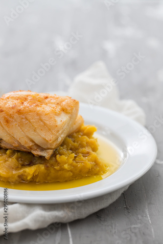 cod fish with mashed potato and olive oil on white dish