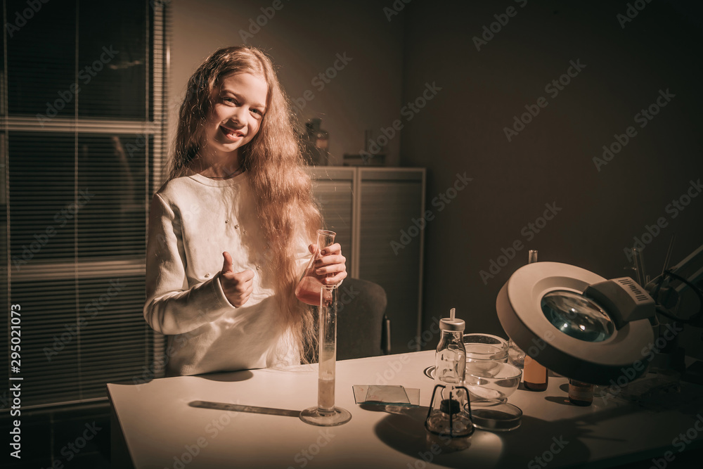 cheerful girl schoolgirl standing near the table in the chemist
