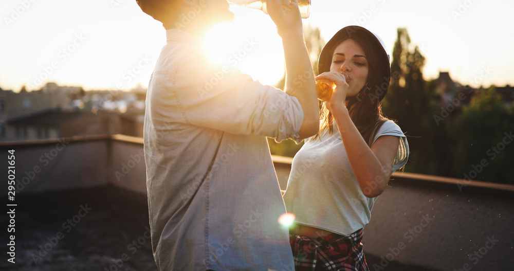 Fototapeta premium Happy young couple enjoying drinks and balcony