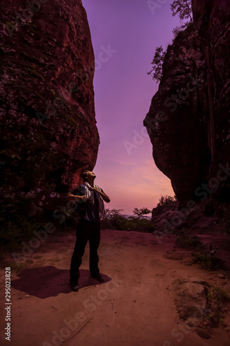 Hiker enjoying the view, against silhouette of rock mountains at sunset, Three whale rock mountain at Phu Sing , Bueng Kan Province,Thailand