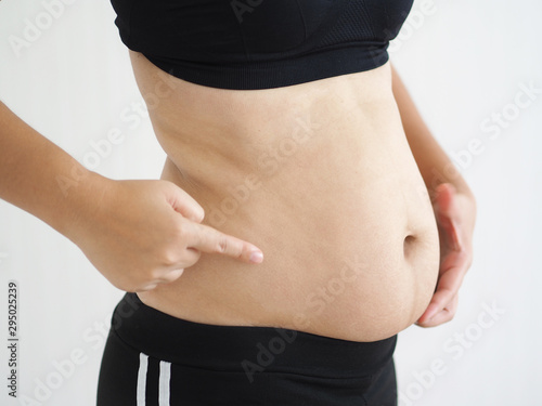 cellulite and belly fat in woman, She pointing her abdomen near waist cause of fatty from weight and loss of collagen use for anti cellulite and body firming gel,cream product or liposuction concept.