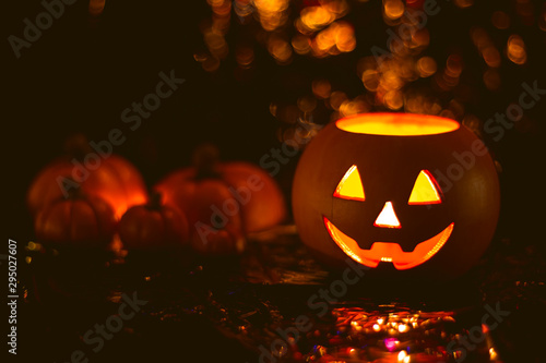Halloween pumpkin head Jack lantern next to several pumpkins on bright orange background
