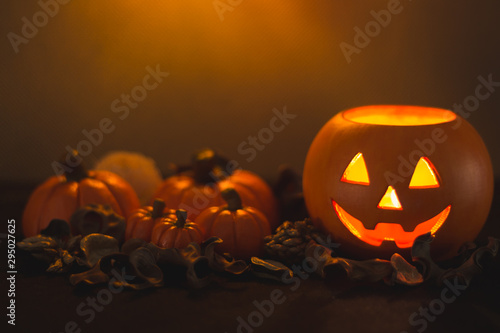 Halloween pumpkin head Jack lantern next to several pumpkins on orange background