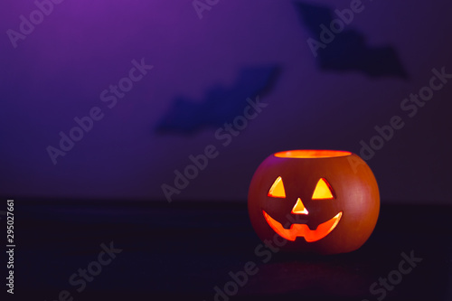 Halloween pumpkin Jack lantern on a purple background with bats