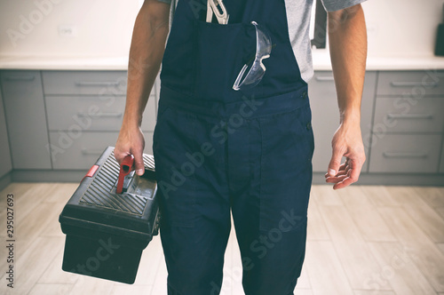 Fotografie The repairer is coming in the house with toolbox in his hand