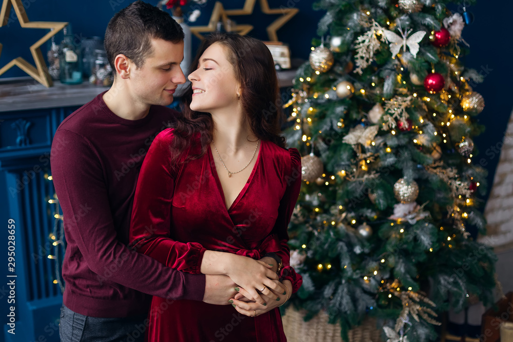 the guy hugs the girl and wants to kiss near the Christmas tree the guy hugs the girl and wants to kiss near the Christmas tree