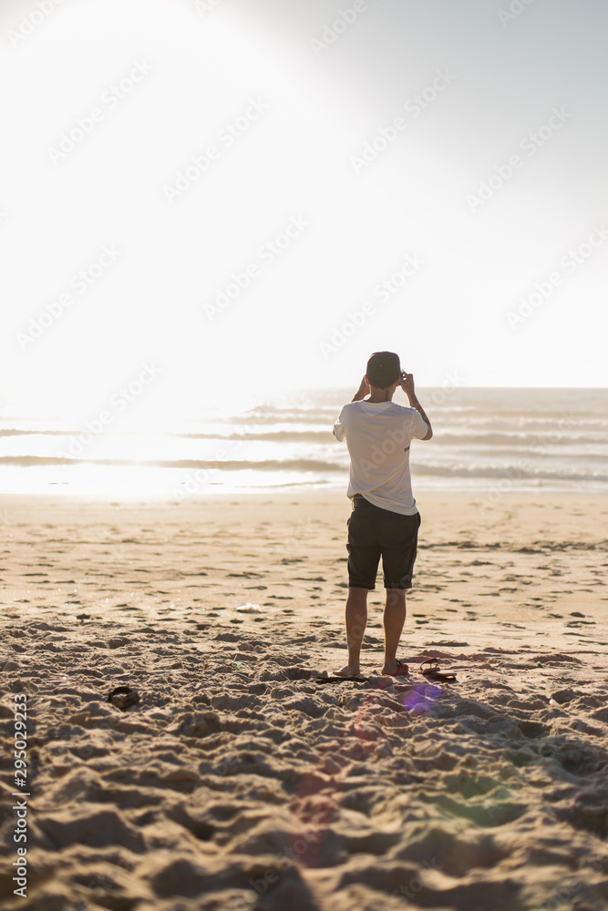 Jeune homme de dos prend une photo de l'océan Stock Photo | Adobe Stock