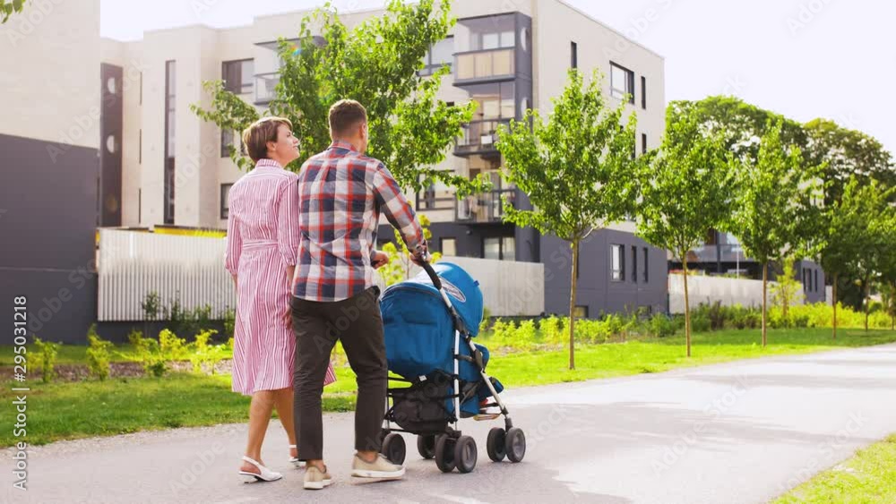 family, leisure and people concept - happy mother and father with little son in stroller walking along city street family, leisure and people concept - happy mother and father with little son in stroller walking along city street