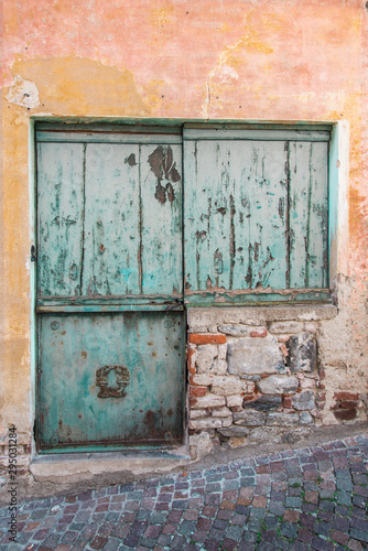 une vieille porte en bois de couleur bleu vert sur un vieux mur orange décrépi  © david