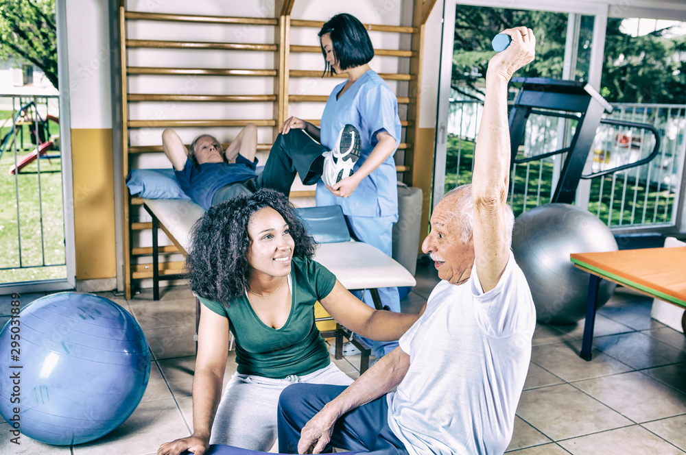 Fototapeta premium Senior retired people keeping fit in the gym with trainer
