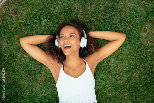 Young african woman in grass listening music