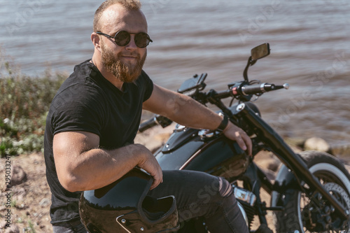 Handsome confident man sitting on a bike holding helmet © Viacheslav Yakobchuk