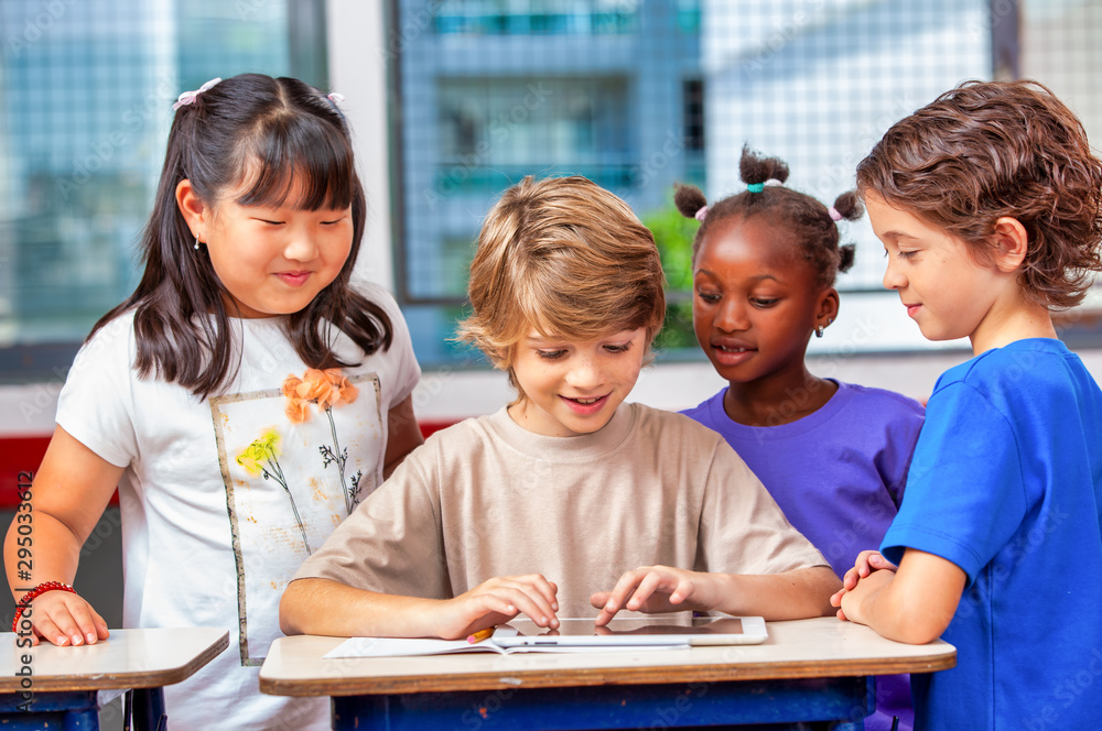 Multi ethnic elementary classroom. Four classmates enjoying school time Multi ethnic elementary classroom. Four classmates enjoying school time