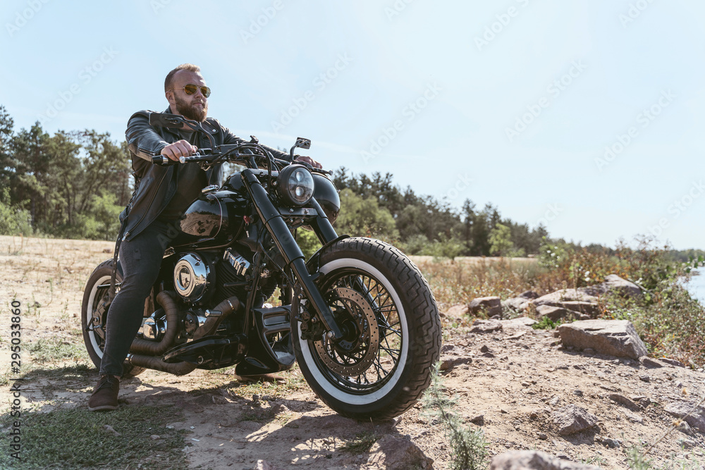 Handsome bearded biker in leather jacket sitting on his bike Handsome bearded biker in leather jacket sitting on his bike