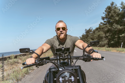 Sexy bearded biker with sigar riding his motorcycle