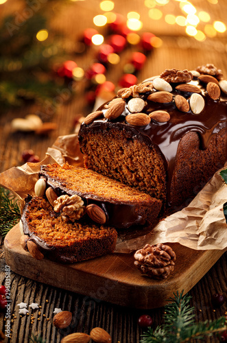 Quadro su tela Christmas gingerbread cake covered with chocolate and decorated with nuts and almonds on the holiday table
