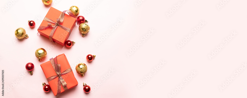 Christmas gift box with satin ribbon, gold and red balls on a pink background. Winter, new year concept. Christmas gift box with satin ribbon, gold and red balls on a pink background. Winter, new year concept.