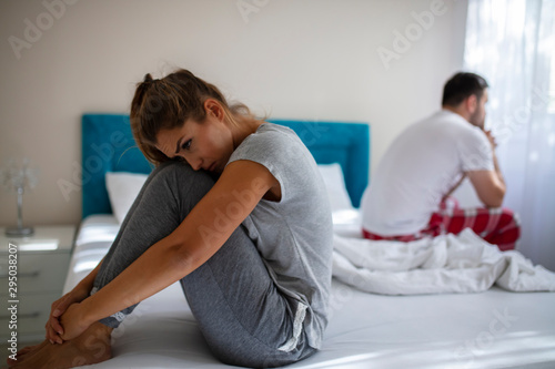 Blurred background of newlyweds have problems fighting in bed. Sleepy married couple have such serious health problem as erection & snoring. Wife is sulky & husband has erectile dysfunction. photo