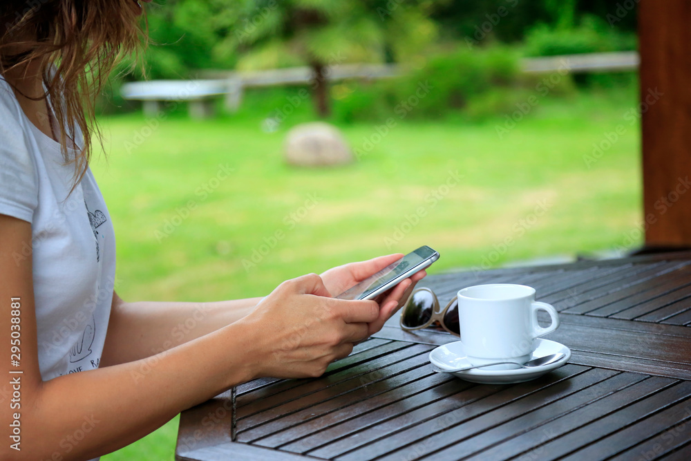 Woman with phone and cup of coffee in the garden Woman with phone and cup of coffee in the garden
