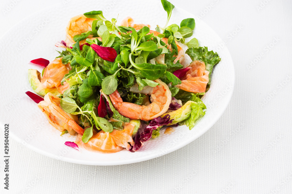 Healthy Salad. Recipe for fresh seafood. Grilled shrimps, prawns, fresh salad lettuce and avocado slices. Healthy Eating. White background. Horizontal photo.