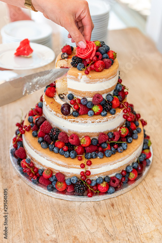 Cutting a wedding cake with a lot of fruit photo