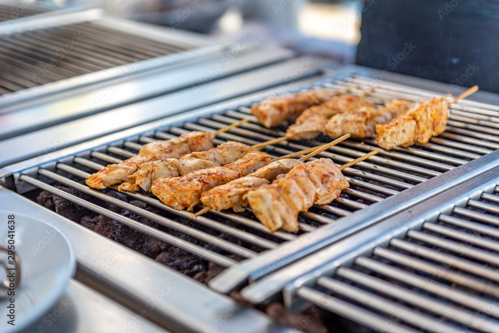 Grilling chicken skewers and hamburgers on a barbecue in a restaurant