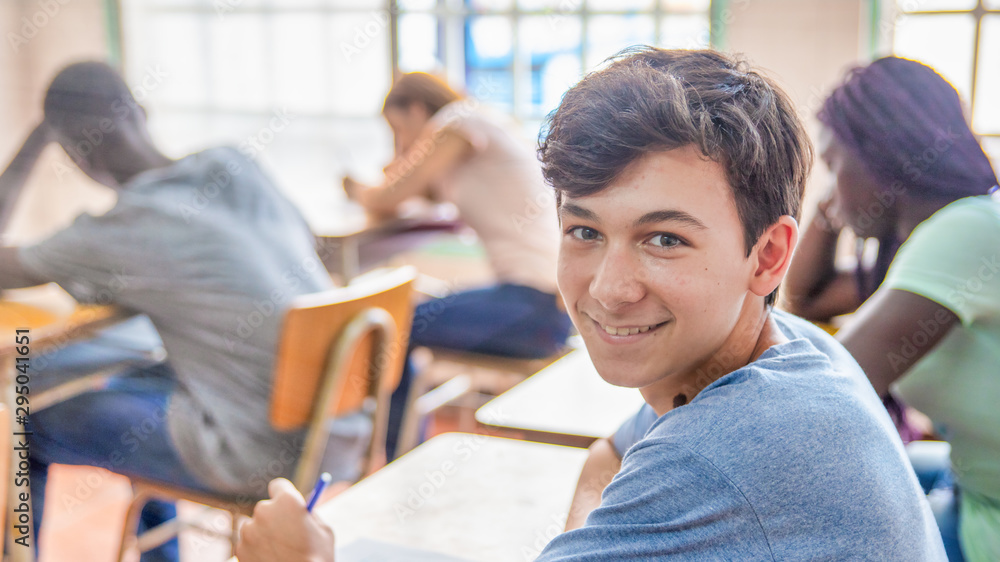 Confident caucasian teenager boy in the classroom doing school test Confident caucasian teenager boy in the classroom doing school test