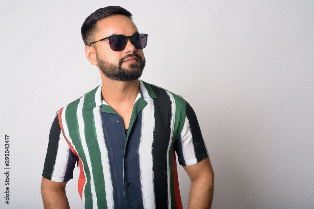 Portrait of young handsome bearded Indian man thinking with sunglasses Portrait of young handsome bearded Indian man thinking with sunglasses