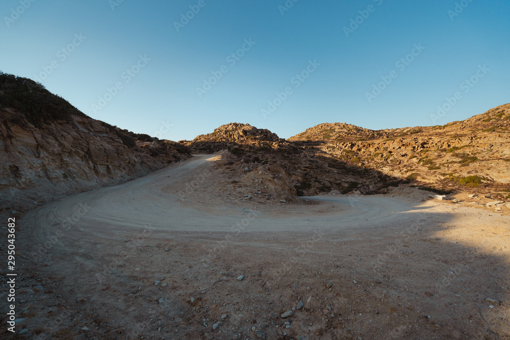 Bend in an arid road in Ios, Greece. Well travelled road with rocky background. 