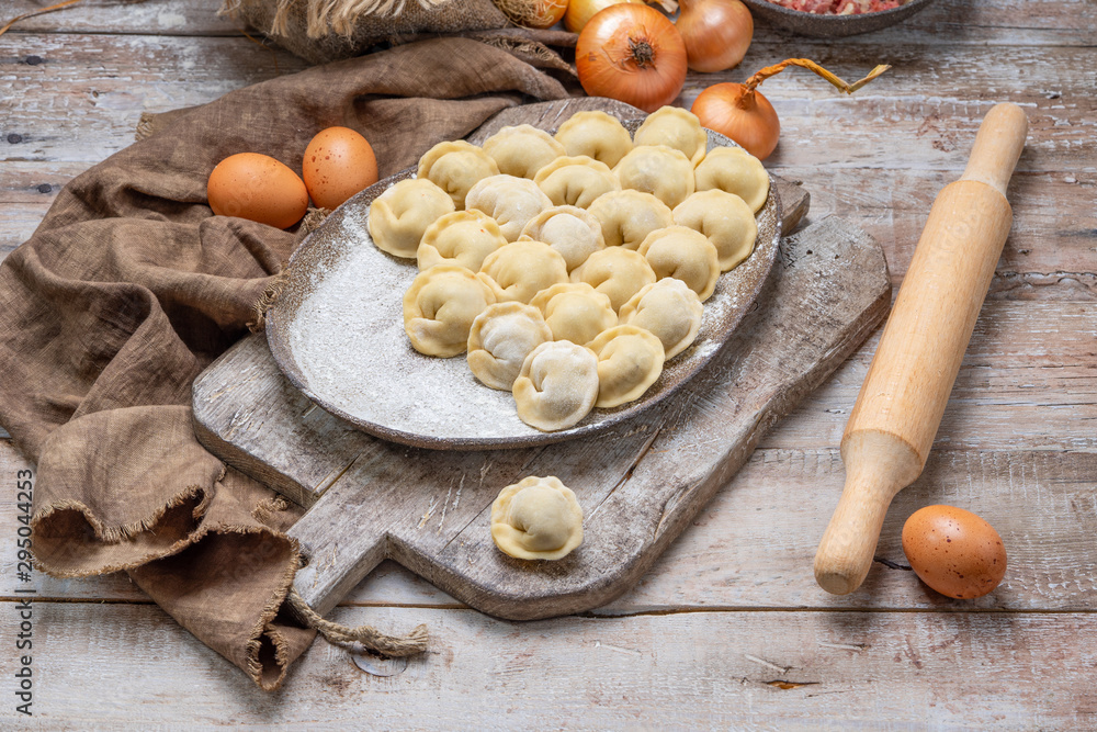uncooked meat dumplings - russian pelmeni on cutting board and ingredients for homemade pelmeni on wooden table. Process of making pelmeni, ravioli or dumplings with meat uncooked meat dumplings - russian pelmeni on cutting board and ingredients for homemade pelmeni on wooden table. Process of making pelmeni, ravioli or dumplings with meat