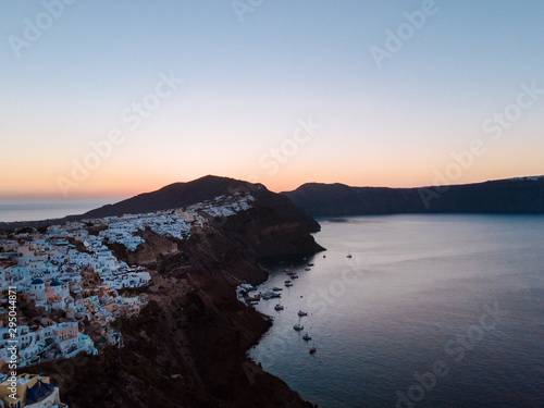 Aerial drone shot of the Santorini caldera at sunrise. Beautiful quiet morning with calm waters and the iconic white houses of Santorini.  photo