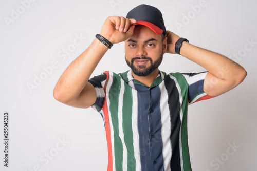 Portrait of young handsome bearded Indian man wearing hat