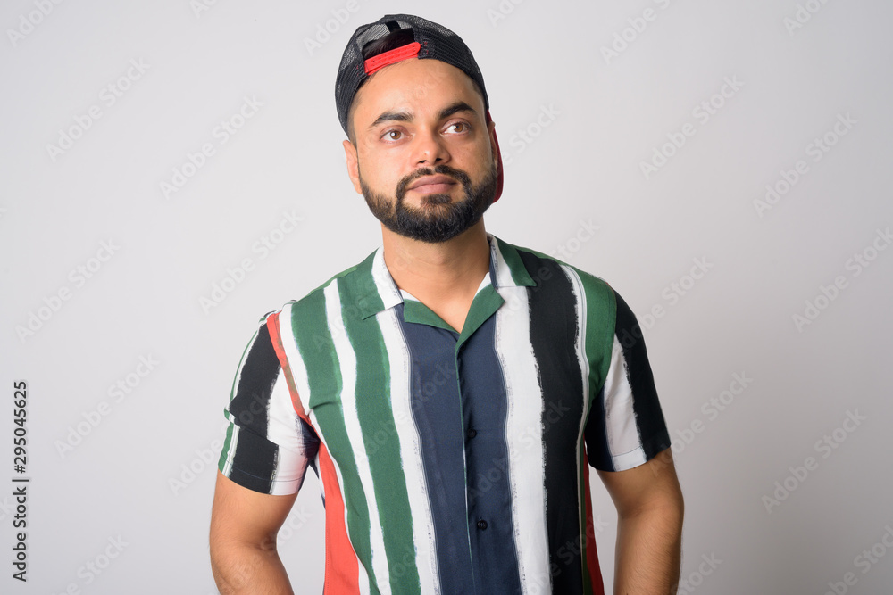 Portrait of young handsome bearded Indian man with hat thinking Portrait of young handsome bearded Indian man with hat thinking