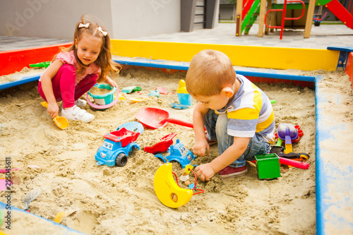 Cuadro en lienzo Little boy and girl playing with sand at modern playground