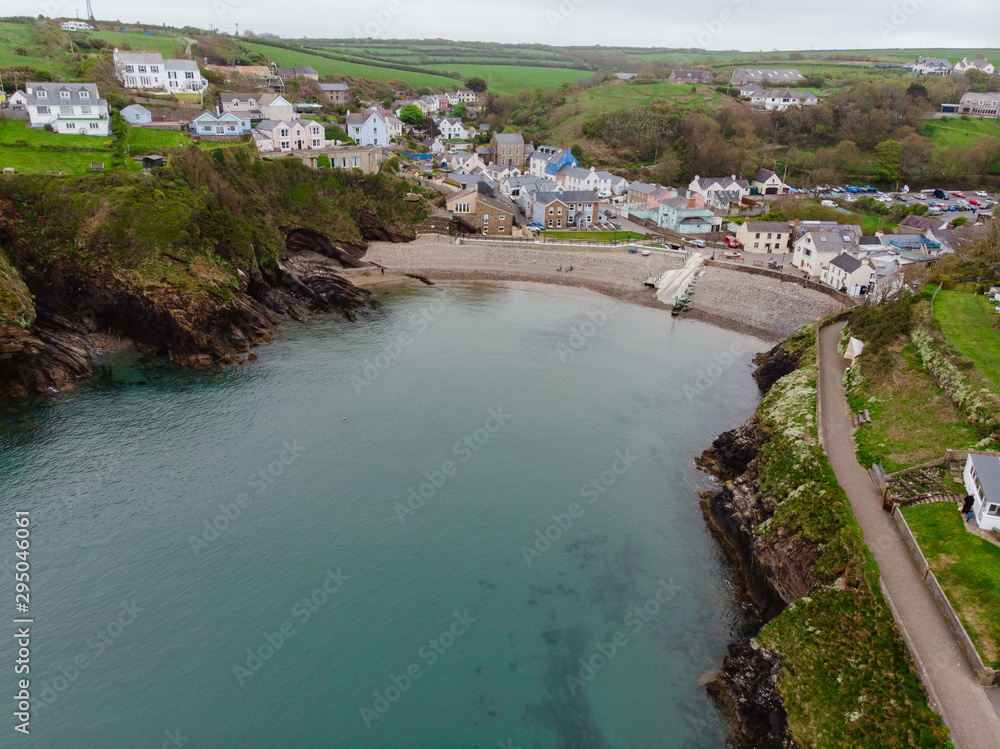 Aerial drone shot of a little coastal town in Wales. Beautiful landscape surrounding the town, with moody sky. 