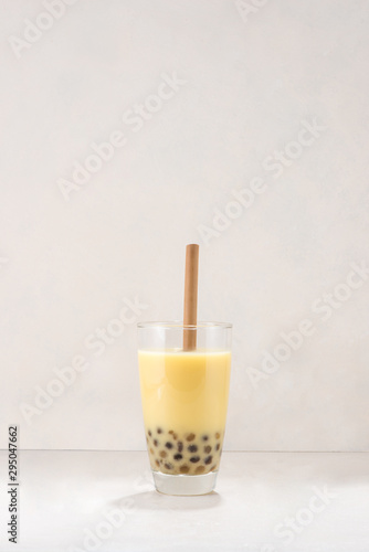 Bubble boba tea with milk and tapioca pearls in glass on white background