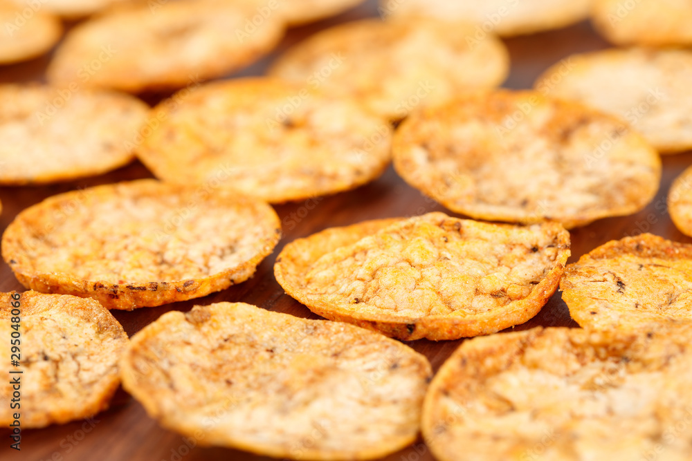Close up of organic, crispy, baked, whole grain rice chips with tomato and paprika spices. Gluten free healthy snack on a wooden background. Close up of organic, crispy, baked, whole grain rice chips with tomato and paprika spices. Gluten free healthy snack on a wooden background.