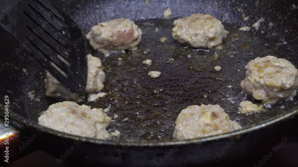 female hand flips meatballs in a pan. Fry in oil. female hand flips meatballs in a pan. Fry in oil.