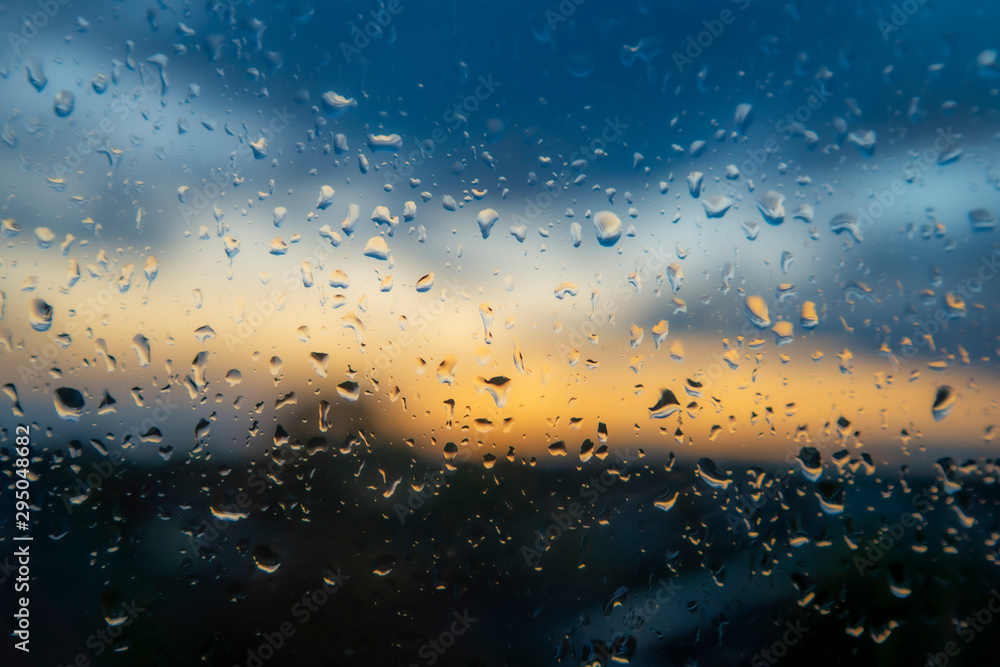 Colorful sunset through wet window glass