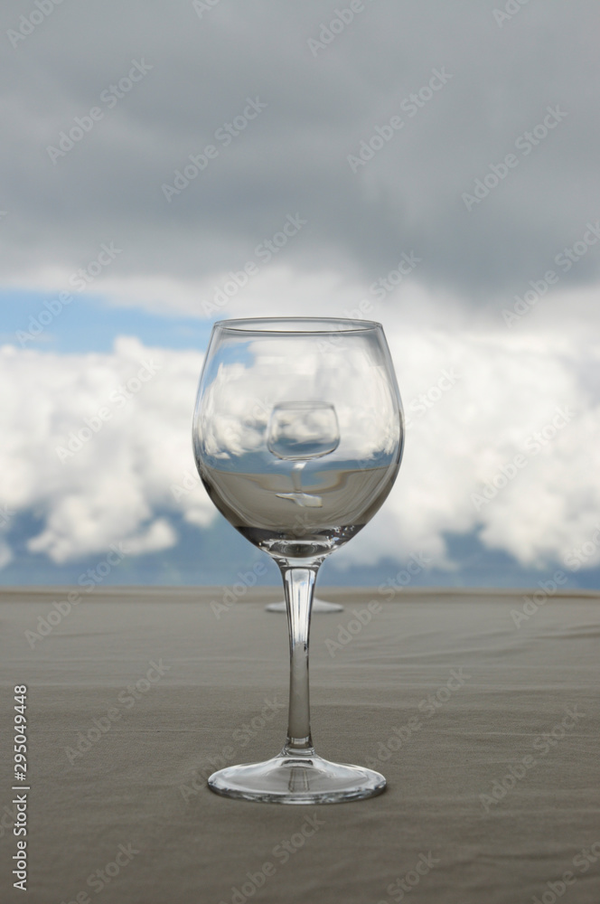 Empty transparent glass on beige table, in which reflected white clouds Empty transparent glass on beige table, in which reflected white clouds