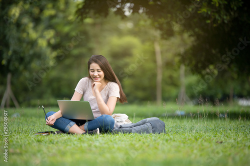 Confident smiling pretty young woman sitting on workplace in outdoor with laptop. Working concept © Oulaphone