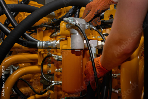Low key photo of hydraulic pipes maintenance on heavy industry machine.