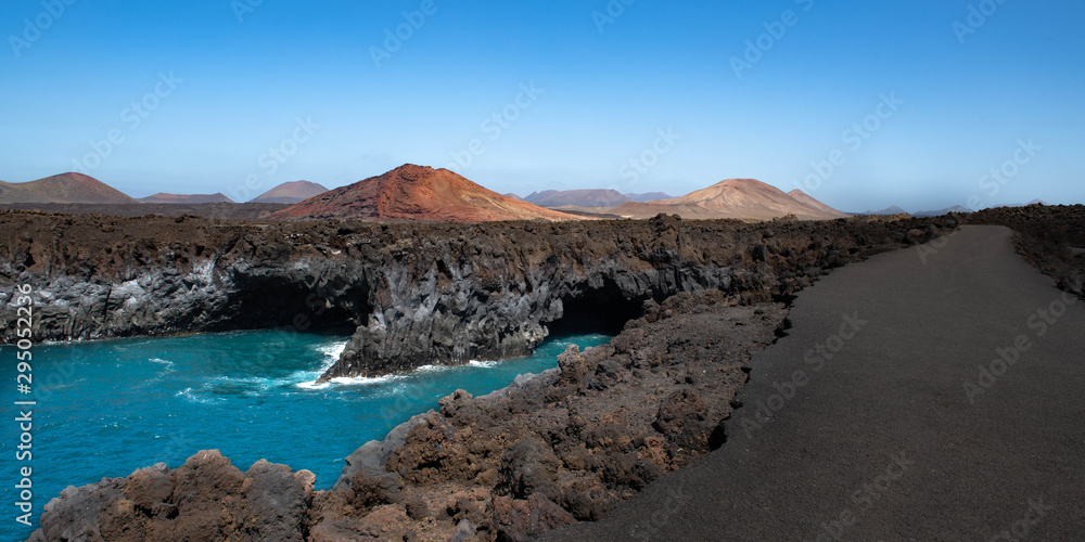 Los Hervideros lava caves (cliffs) in Lanzarote, Canary islands, Spain with Montana Bermeja volcano in the background