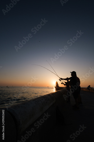 fishermen on pier at sunset