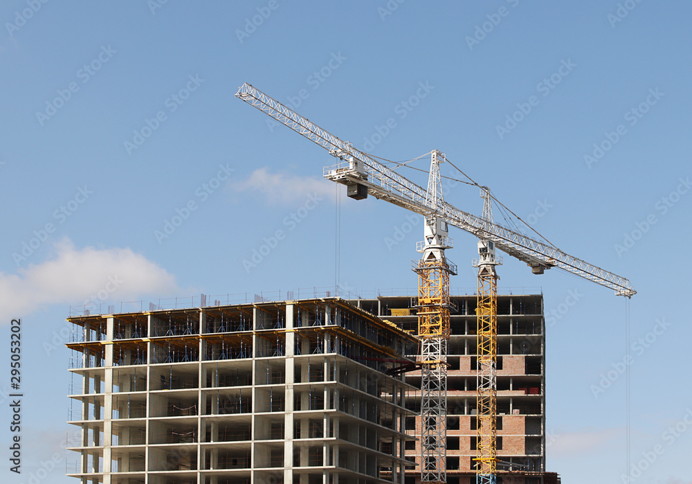 Use of high tower frame metal cranes in construction. Panorama of the development of the city against the blue sky. Work in real estate and urbanization. Metal constructions in business development