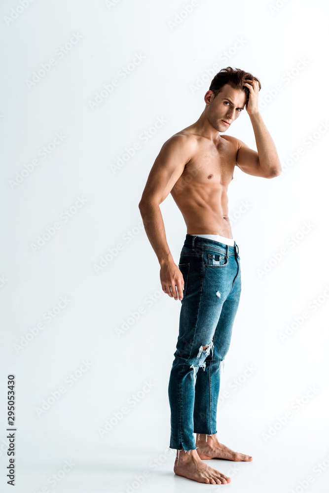 shirtless man touching hair and standing on white